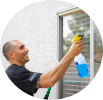 A man washing an exterior window of a house