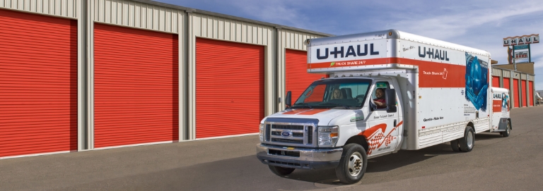 A U-Haul rental truck next to a U-Haul equipment storage facility