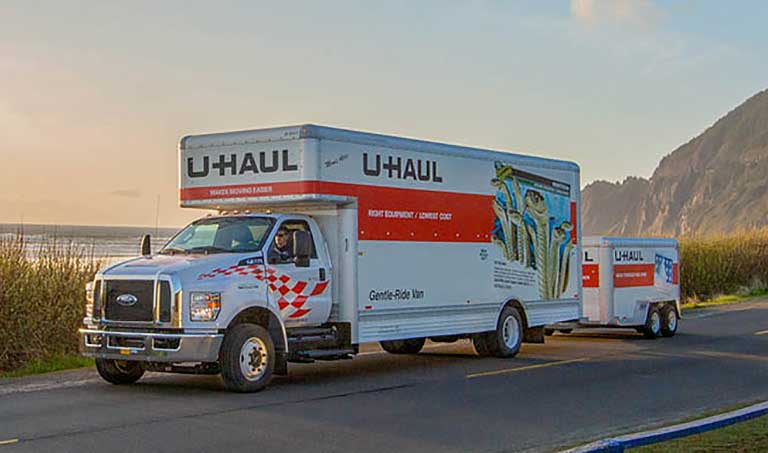 A U-Haul rental truck towing a cargo trailer