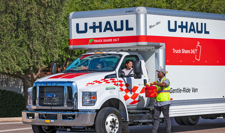 A roadside assistance worker adding fuel to a U-Haul rental truck