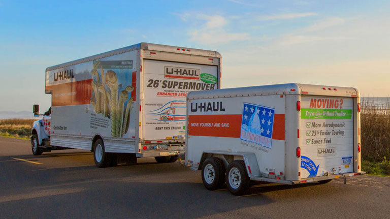 A U-Haul rental truck towing a cargo trailer