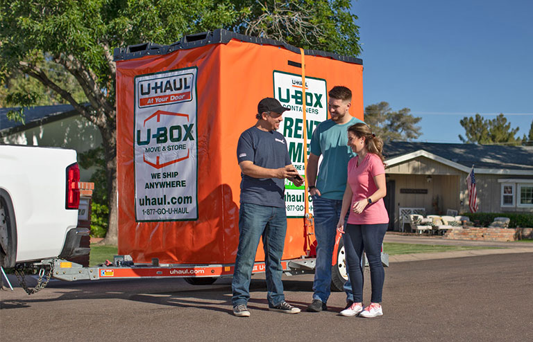 Three people standing next to a U-Box container