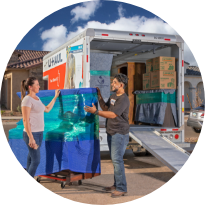 A man and a woman unloading wrapped furniture from a moving truck