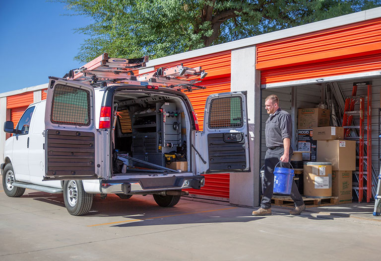 A man loading supplies into a work van from a business storage unit
