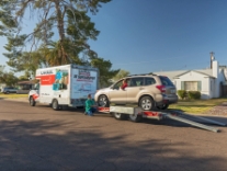 A moving professional loading a vehicle onto an auto transport trailer
