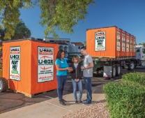 A couple and a moving professional reviewing U-Box containers on a truck
