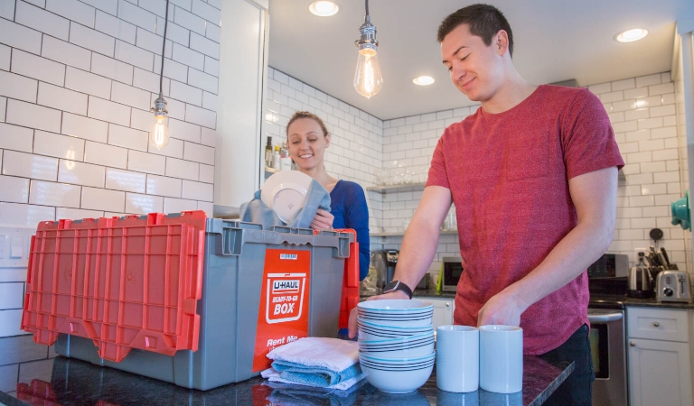 A man and a woman loading items into a U-Haul Plastic Box