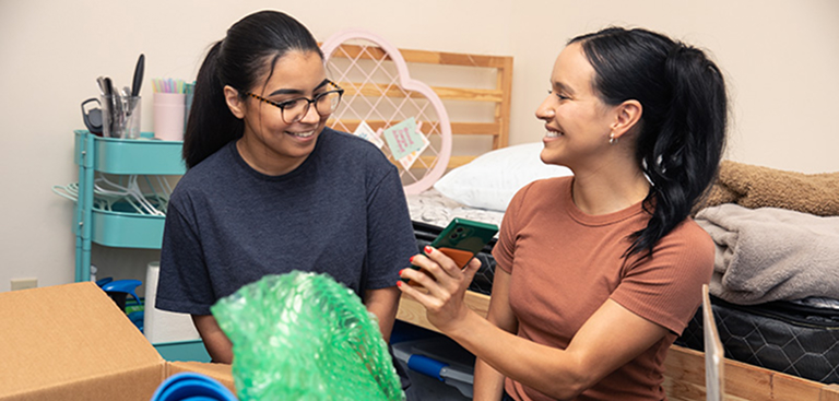 Two women loading items into Collegeboxes in their dorm room
