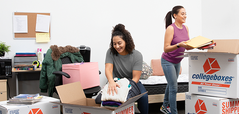Two women loading items into Collegeboxes in their dorm room
