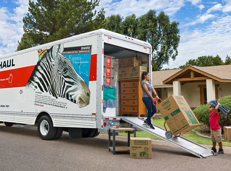 A woman unloading a box on a dolly from a U-Haul rental truck