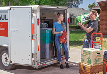 A couple loading a U-Haul trailer in front of their home