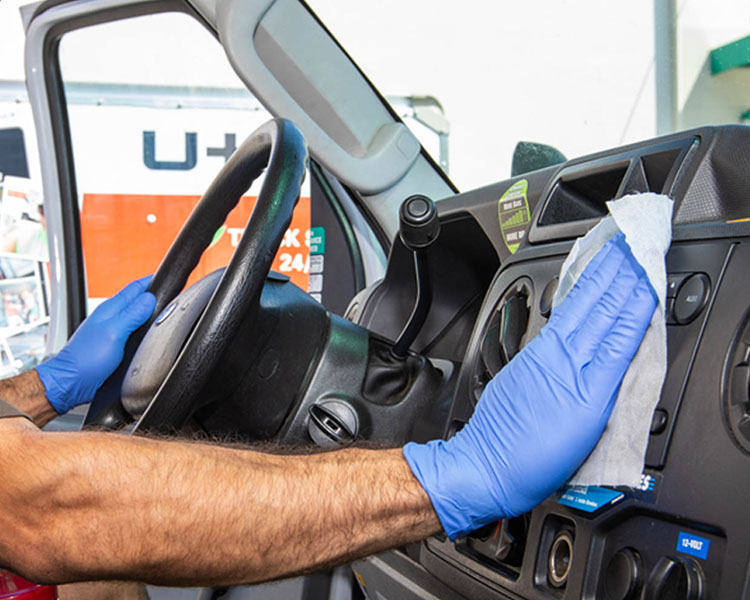 U-Haul center employee sanitizing the interior of a moving truck