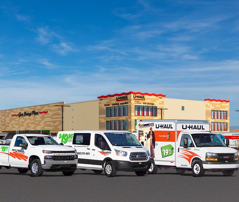 A U-Haul Pickup Truck, Cargo Van, and 10ft Moving Truck lined up in from of a U-Haul Rental Center
