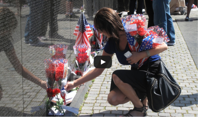 A woman placing flowers at a war memorial in Washington D.C.