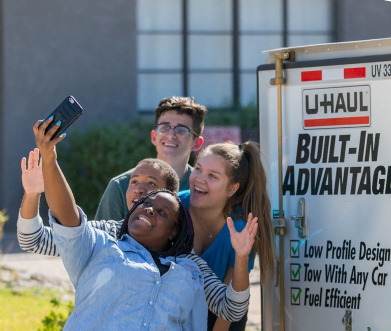 A group of friends taking a selfie next to a U-Haul rental truck