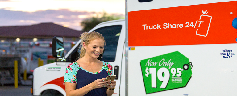 A woman using a mobile device to rent a U-Haul Moving Truck