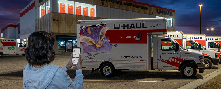 A woman using a mobile device to start a contactless pickup of a U-Haul Moving Truck rental