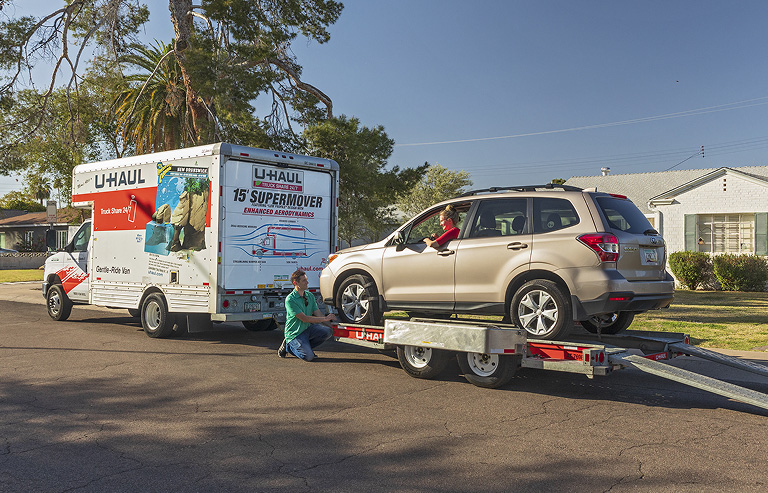 A couple securing an SUV to a U-Haul Auto Transporter