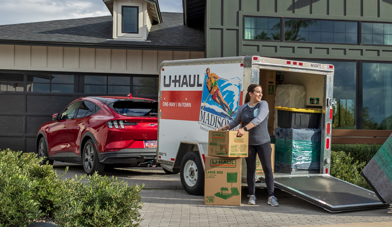 A couple loading moving boxes into a U-Haul Cargo Trailer