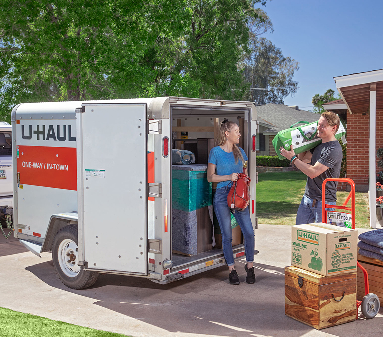 A couple loading items into a U-Haul cargo trailer