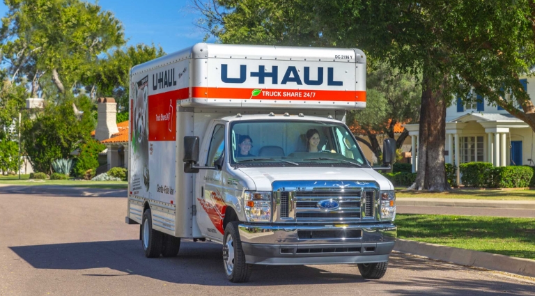 A couple driving a U-Haul truck through a residential neighborhood