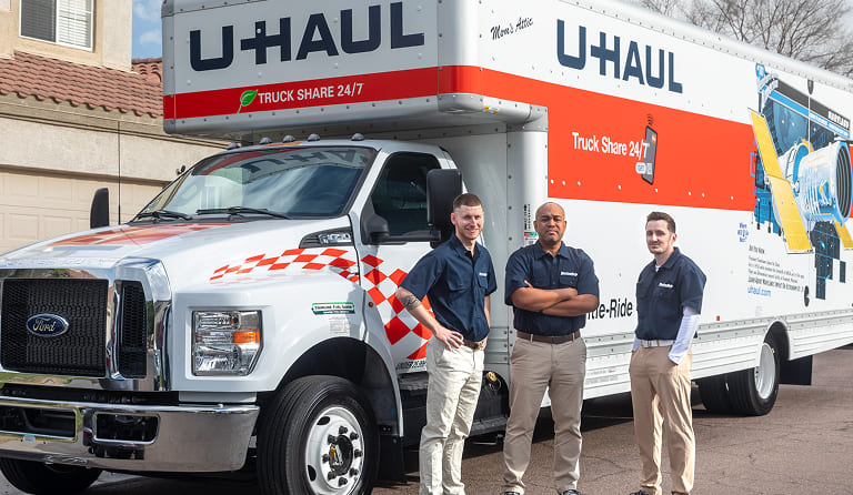 A moving help crew standing in front of a U-Haul moving truck