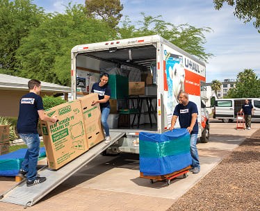 Moving Help crew moving a large TV box up a ramp into a U-Haul moving truck