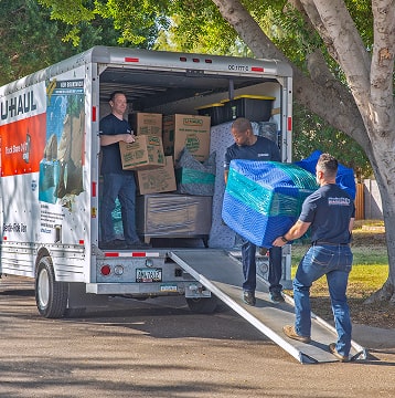 Moving Helpers loading a large couch into a U-Haul moving truck