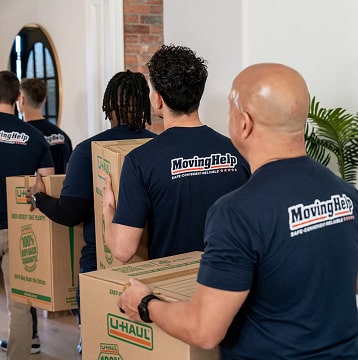 Group of Moving helpers with loaded boxes walking into a family's home