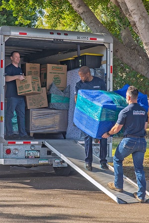 Moving Helpers loading a large couch into a U-Haul moving truck