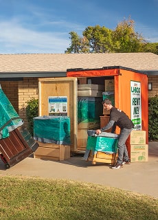Moving Helpers unloading furniture from a U-Box container in front of a family's home