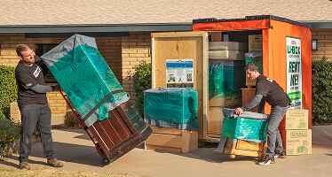 Moving Helpers unloading furniture from a U-Box container in front of a family's home