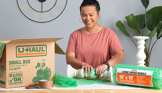 A woman packing items into a moving box