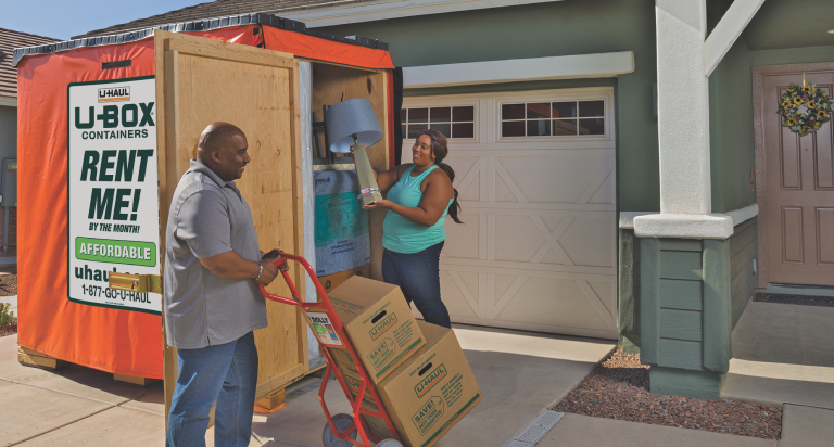 A couple loading a U-Box portable storage container outside their home