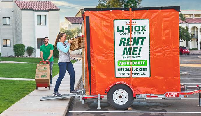 Couple loading boxes into a UBox on a trailer