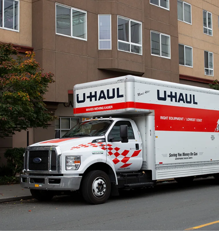 U-Haul moving truck parked on the street infront of an apartment complex.